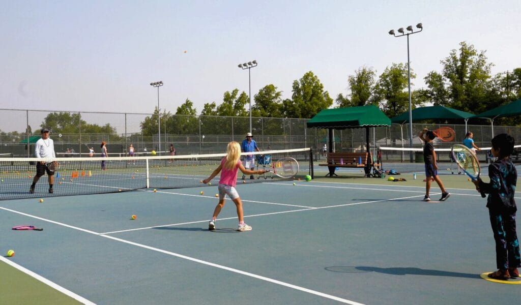 junior tennis camp players training with coach at Reno Tennis Center